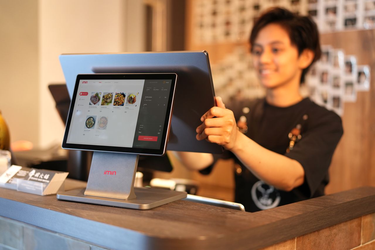 Mastering the First Impression: Your intriguing post title goes here Smiling cashier using a touchscreen POS system in a modern retail environment.