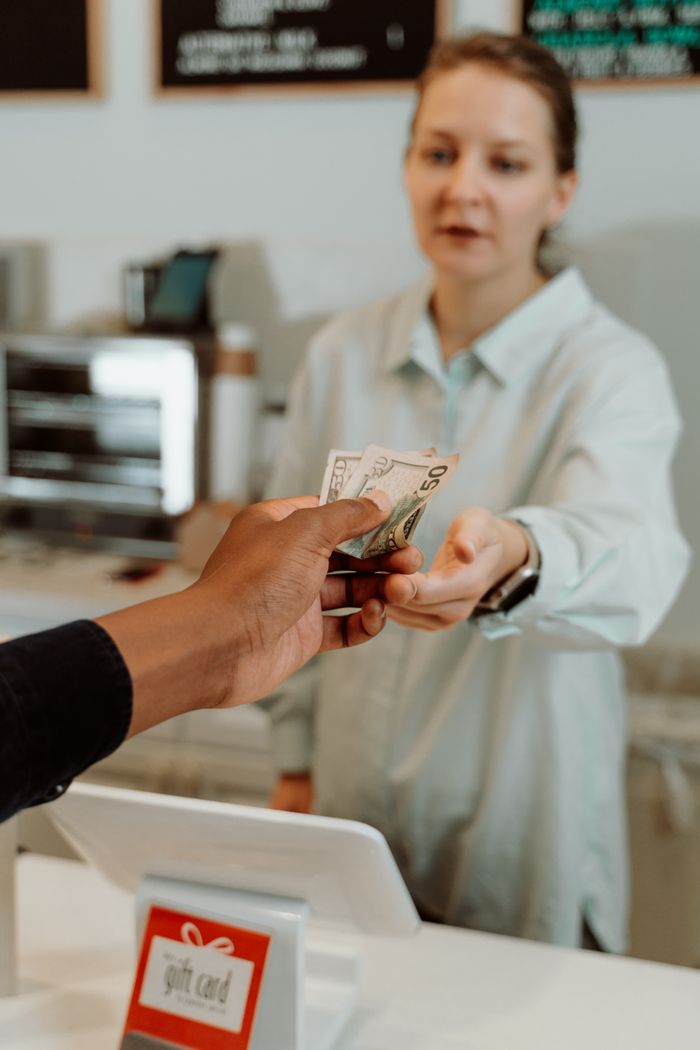 Crafting Captivating Headlines: Your awesome post title goes here A female cashier receiving cash payment from a customer at a retail store.