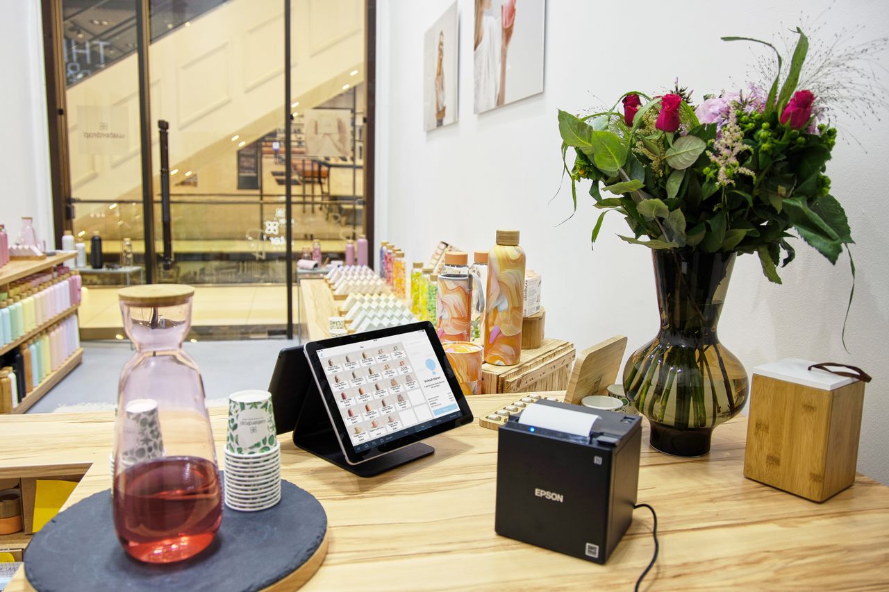 get-in-touch A stylish store checkout counter featuring a floral bouquet and digital payment system.