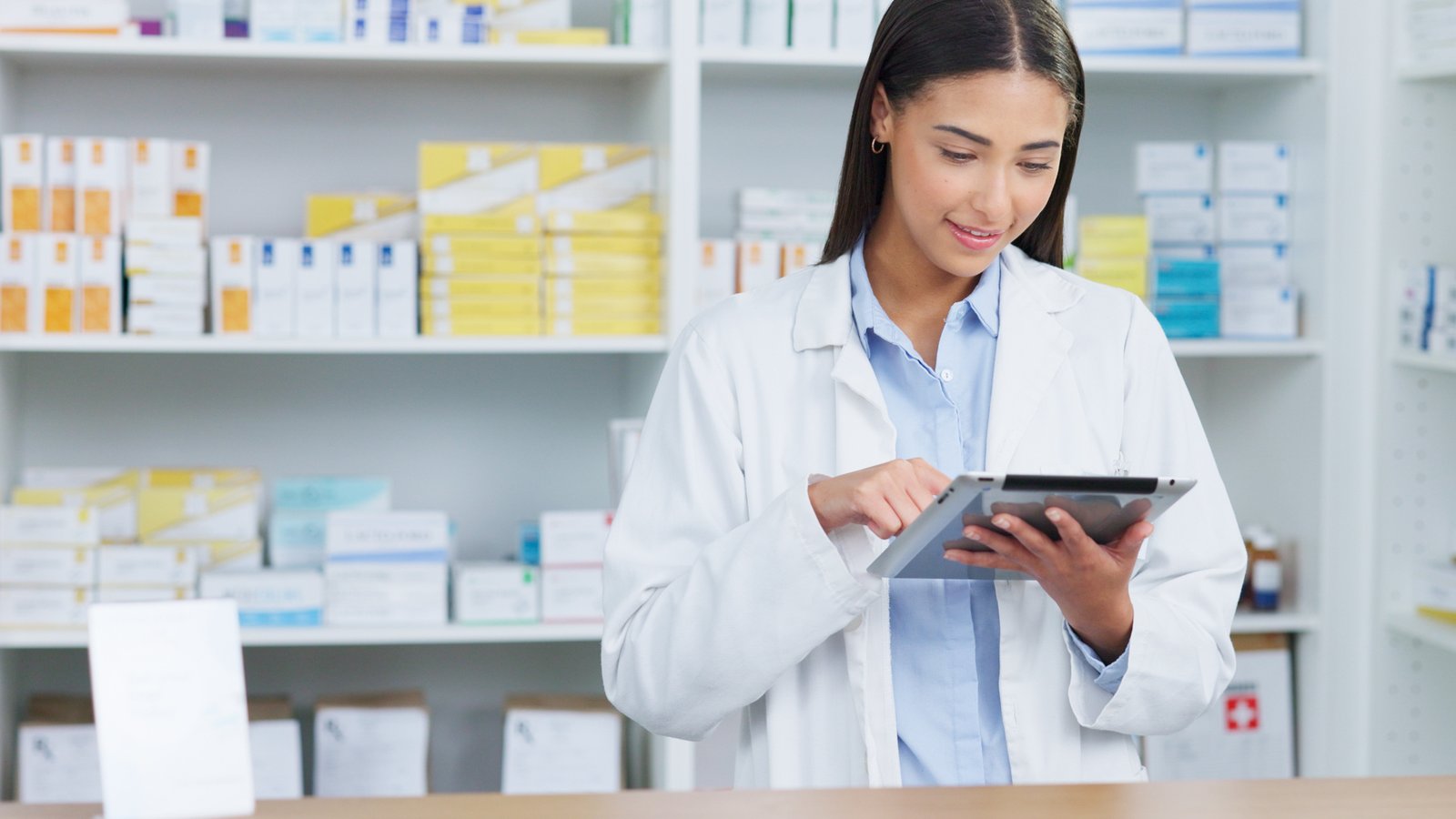 Farmacéutica joven revisa una tableta en el mostrador de su farmacia